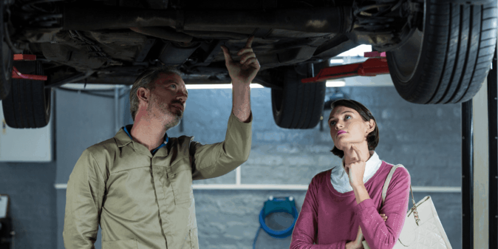 A man and woman inspecting the engine of a car, discussing its components and maintenance.
